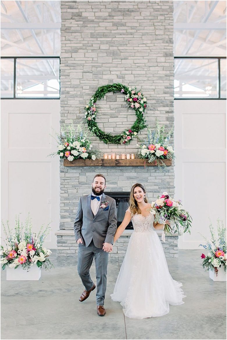 Wedding ceremony stone fireplace, mantle, large wreath, joyful couple, married